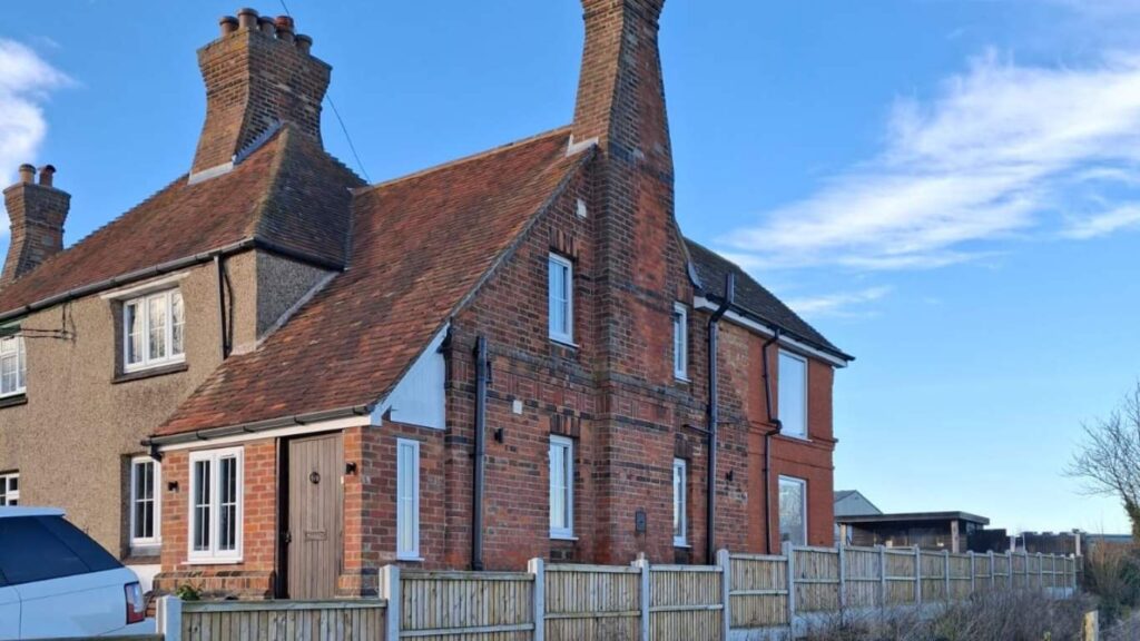 Old English-style house with red brick, steep roof, and prominent chimneys