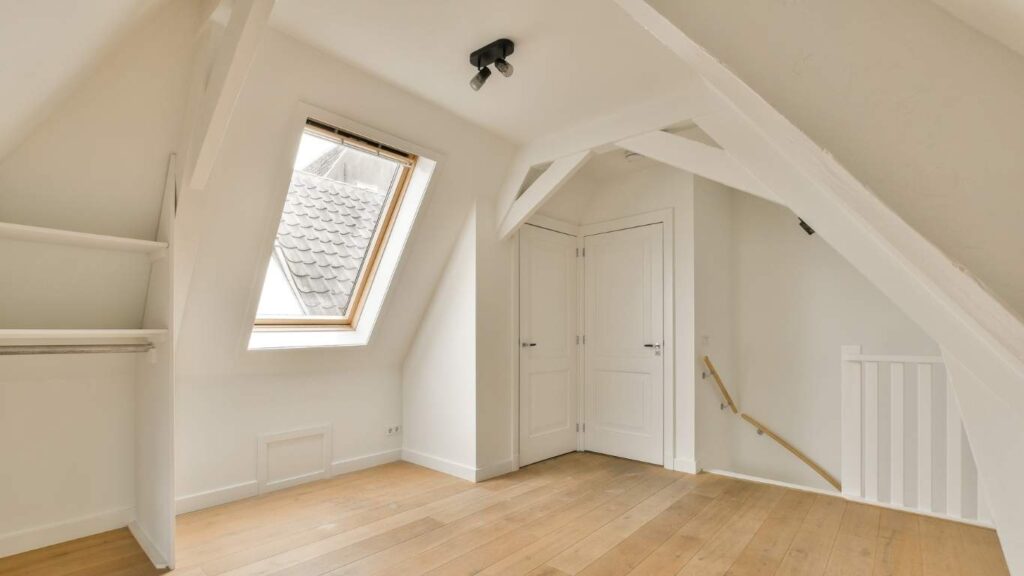 Completed loft conversion with skylight, white walls, and wood flooring