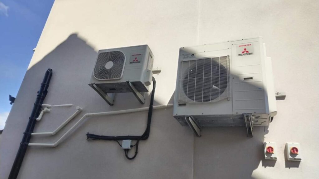 Two Mitsubishi inverter AC outdoor units installed on a building wall, showing proper setup for efficient cooling